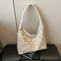 Sac Hobo à fleurs beige avec bandoulière mince posé sur un banc noir élégant - Blanc Cassé