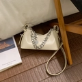 Detail der cremeweißen Ledertasche mit auffälliger Silberkette und verstellbarem Gurt - Weiß