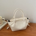 Detail of the white leather handbag featuring a knotted handle and drawstring design - White