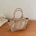 Detail view of beige crossbody bag with knotted handle and side drawstring on wooden table - Khaki