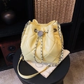 Sac seau jaune matelassé avec chaîne argentée et cordon de serrage sur tabouret - Jaune