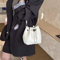 Sac seau matelassé blanc avec chaîne argentée porté par un mannequin au style minimaliste - Blanc Cassé