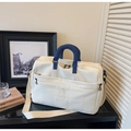 Detail of quilted white travel bag showing brand embroidery and blue handles on a shelf - Off White