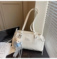 Detail of a creamy white leather shoulder bag with a teddy bear charm and logo plaque - With Charm / Off White