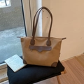 Detalle de bolso tote de lona y cuero con asas dobles resistentes sobre una silla - Caramelo