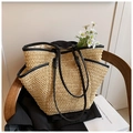 Close-up of a woven straw tote bag featuring black leather handles on a wooden chair - Beige