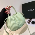 Light green pleated bucket handbag with metallic buckle shown in a stylish hand-held pose - Light Green