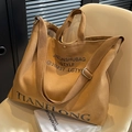 Khaki canvas tote bag with black typography on a chair, large capacity stylish design - Tan