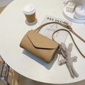 Kaki schoudertas met lychee textuur en schattige konijnenhanger op een witte tafel - Khaki Met Hanger