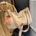 Cream nylon dumpling shoulder bag with peach charm and adjustable strap detail - Cream White With Pendant