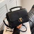 Elegant black textured leather crossbody bag with a gold T-shaped metal clasp and top handle - Black