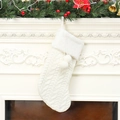 Detail van een witte kabelgebreide kerstsok met nepbont en zachte pluche pompons - Wit