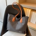 Bolso tote de lona gris con asas de cuero marrón y logo de marca en una silla - Marrón Oscuro