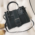 Borsa a tracolla grigio scuro con cuciture bianche e fibbia metallica su una sedia bianca - Nero