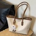 Minimalistische Tote-Bag in Creme und Braun mit Plüschmonster-Anhänger auf Steinsockel - Gebrochenes Weiß