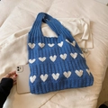 Bolso tote de punto azul con diseño de corazones y asas junto a un smartphone - Azul
