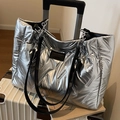 Borsa tote trapuntata argento metallizzato con catena nera su una valigia bianca - Argento