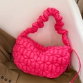 Vibrant pink quilted crescent shoulder bag with elastic ruffled strap on a chair - Deep Pink