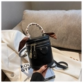 Detail of a black leather bucket bag with leopard silk scarf and gold zippers on white blazer - Black