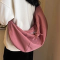 Grand sac bandoulière croissant rose poudré en toile avec pompon porté par un modèle - Rose