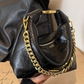 Quilted black leather handbag featuring a vintage gold chain handle and glossy finish - Black
