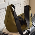 Olive green nylon crescent shoulder bag with adjustable wide strap on a sofa - Green