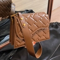 Chic brown quilted crossbody bag with golden hardware and wide strap shown on black satin - Brown