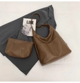 Braune Hobo-Tasche aus Leder mit passender Tasche auf grauem Blazer und Büchern - Schultertaschen-Set / Sandfarben