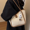 Large cream tote bag with brown trim and plush toy charm shown on a female model - Black without Pendant
