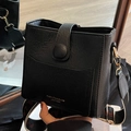 Bolso saco negro de cuero con textura, correa ancha estampada y detalles dorados - Negro