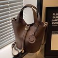Bolso saco de cuero marrón oscuro con textura de lichi, cierre dorado y colgante - café