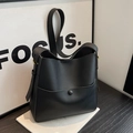 Bolso tipo cubo minimalista en cuero negro con correa ajustable y detalles metálicos dorados - Negro