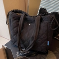 Black quilted tote bag with drawstring closure and soft padded handles in a minimalist style - Black
