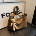 Detalle de bolso hobo de cuero mate con hebilla dorada y colgante de oso tejido - Con Colgante de Oso / Marrón
