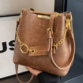 Braune matte Beuteltasche aus Leder mit Goldkette und Doppelriemen in stilvoller Handhaltung - Sandfarben