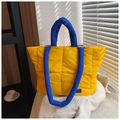Detalle de bolso tote acolchado amarillo con asas azules y costuras cuadradas - 黄色和蓝色
