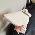 Elegante bolso de hombro triangular color crema con hebilla plateada sostenido en la mano - Blanco