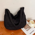 Zwarte gewatteerde tote bag met hartpatroon en brede riem op een bruine lederen stoel - Zwart
