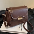 Classic dark brown vintage leather saddle bag with gold lock on a book surface - Brown Style 2