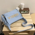 Light blue nylon tote bag with XBOKA patch and adjustable strap on a wooden table - Blue Without Charm