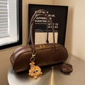 Brown vintage bowling bag with embossed letters and plush charm on a metallic table - Coffee With Pendant