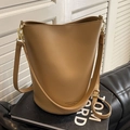 Chic camel brown leather bucket bag with gold hardware and adjustable strap on a sofa - Khaki
