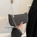 Dark gray denim baguette bag with silver studs and chain strap held by a model - Black