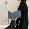 Blue denim underarm bag with silver rivets and chunky metal chain held by hand - Light Blue