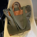 Bolso tote de lona verde oscuro con asas de cuero marrón sobre una silla blanca - Verde Militar