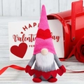 Macro-opname van een roze Valentijnsdag-kabouter met gebreide muts en hartjes op hout - Banner Vasthoudende Stijl