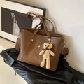 Braune Shopper-Tasche aus Kunstleder mit Goldnieten, breitem Gurt und Bärenanhänger - Mit Anhänger / Braun