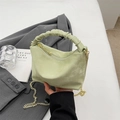 Fashionable mint green pleated handbag with gold chain strap held against grey suit - Green