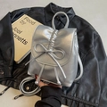 Mini sac à dos argenté avec plis métalliques et nœud décoratif sur fond noir élégant - Argenté