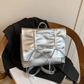 Sac à dos argenté métallisé à plis avec nœuds décoratifs posé sur une chaise en bois - Argenté